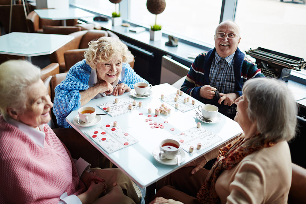 Group of seniors sitting at table playing bingo in memory care services