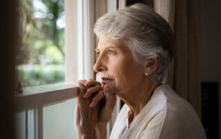 Senior woman with dementia looking lost out window