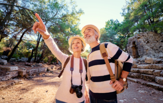 Senior couple hiking outside in wilderness with cameras around necks