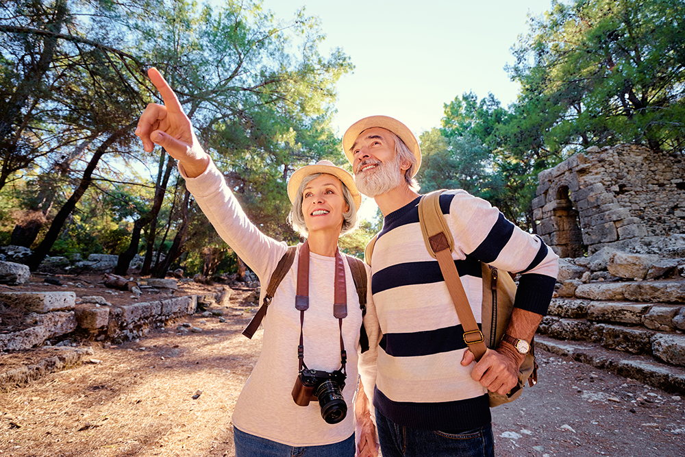 Senior couple hiking outside in wilderness with cameras around necks