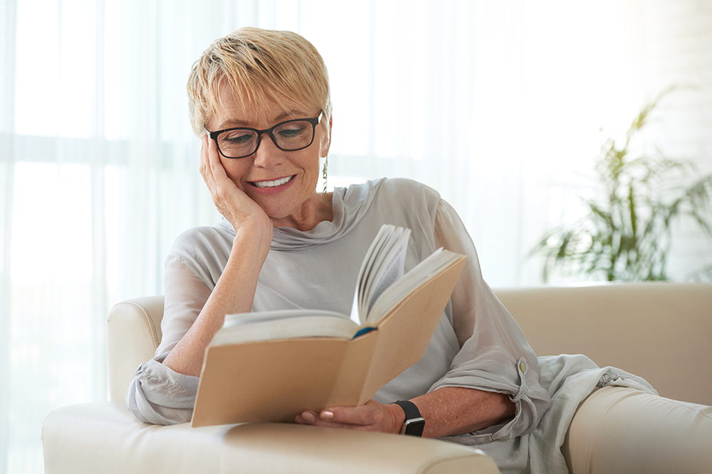 Woman sitting on couch relaxing and reading a book