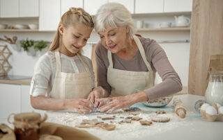 Senior woman baking in kitchen with granddaughter