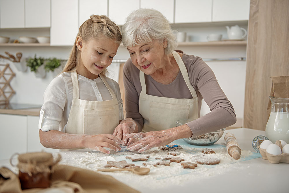 Senior woman baking in kitchen with granddaughter