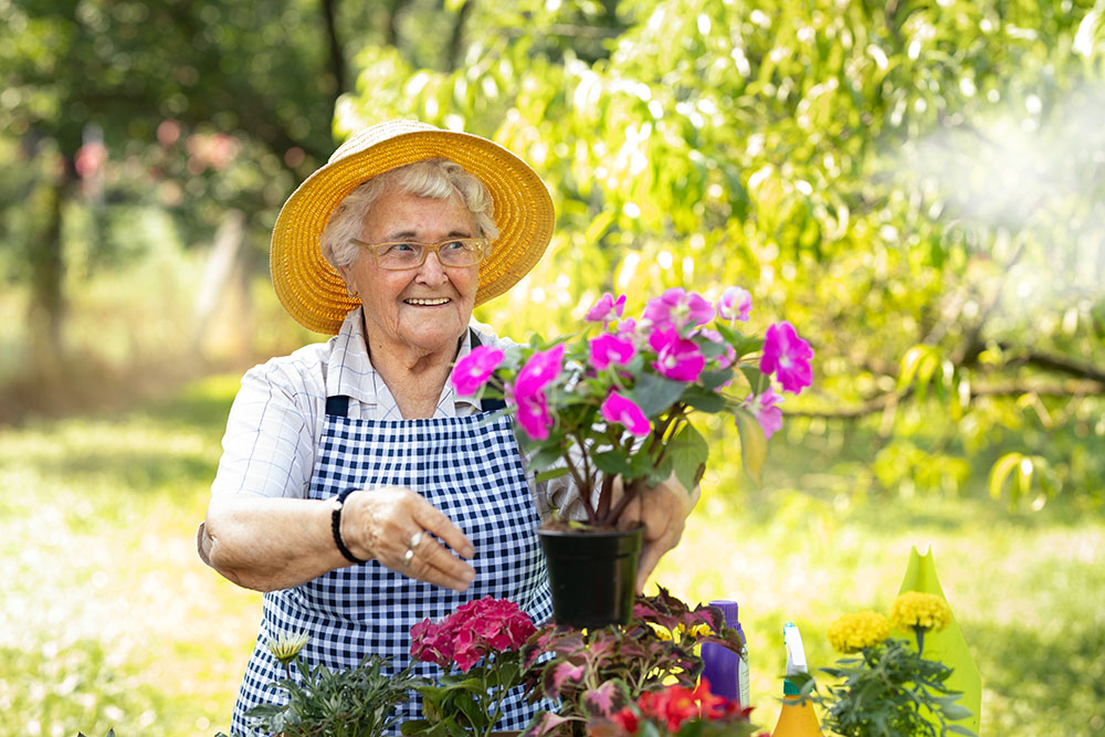 Senior woman tending to container garden in senior living in Carlsbad