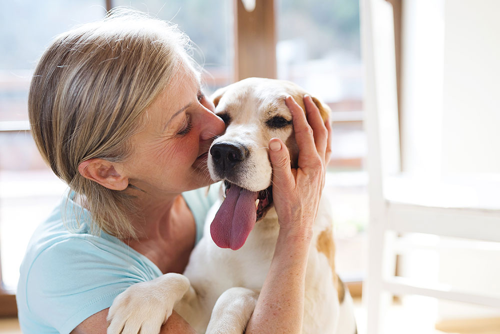 Happy senior woman loving on dog