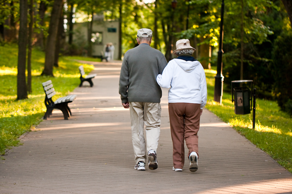 A senior couple strolls through a park