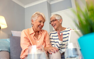 Two senior woman talk and laugh while in memory care in Carlsbad