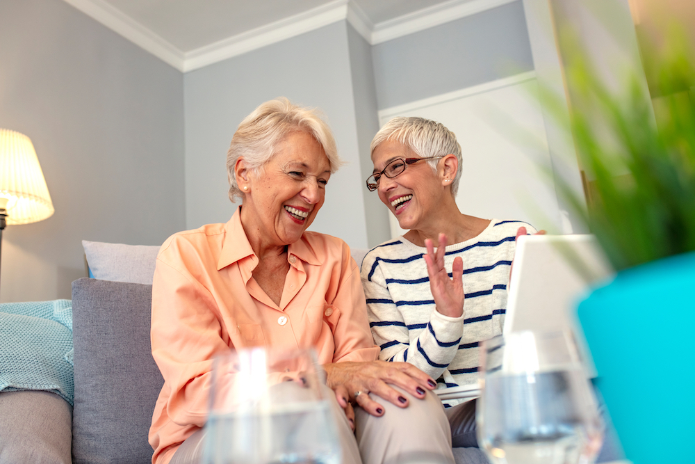 Two senior woman talk and laugh while in memory care in Carlsbad