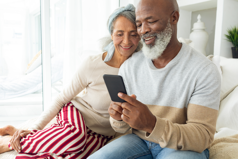 A senior couple uses their smartphone to scroll through retirement options