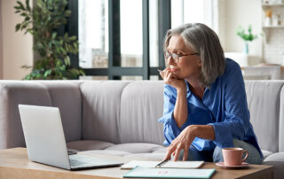 A senior woman uses her computer to look at retirement communities