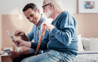 A senior man and his son look at a photo album while at Carlsbad memory care services