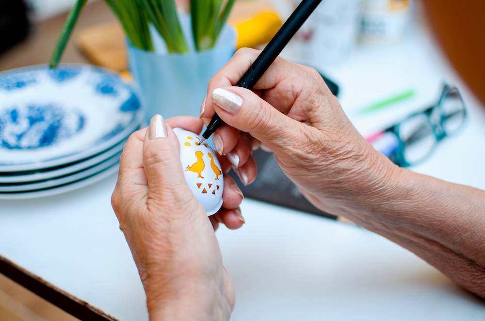 A senior woman holds an egg to decorate it