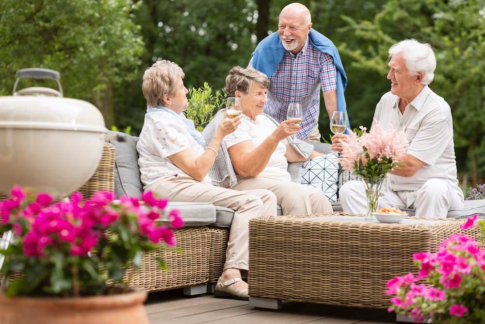 A group of senior enjoy socializing on the patio at assisted living