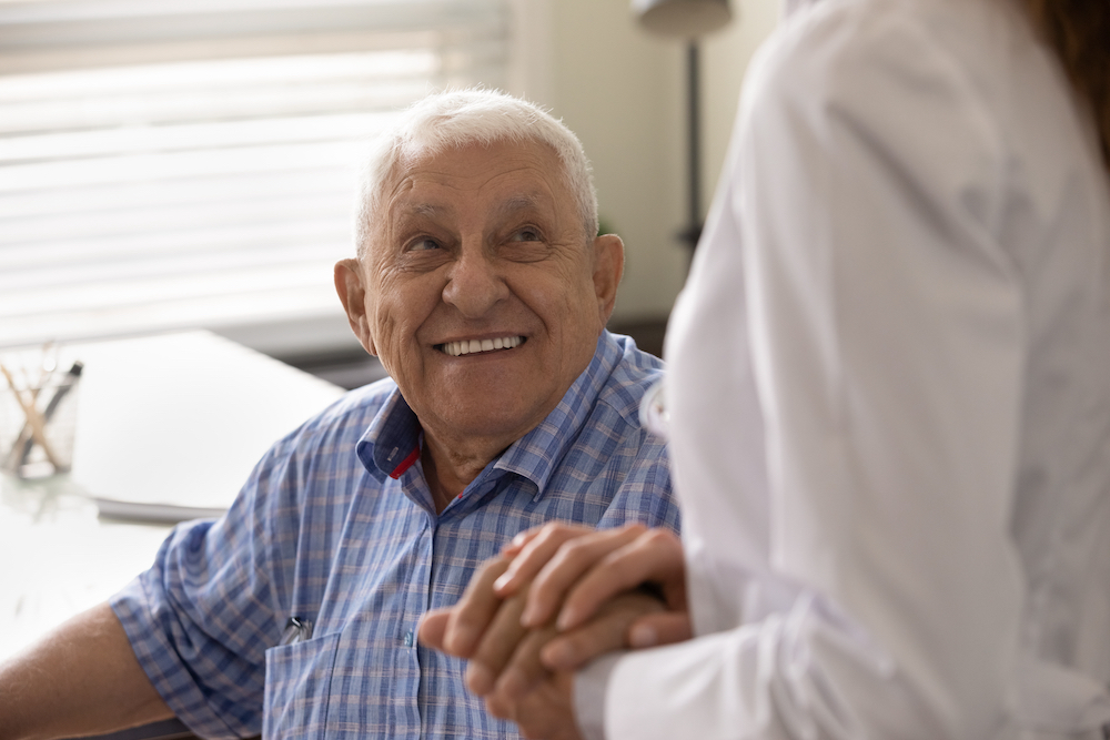 A senior man smiling up at caregiver