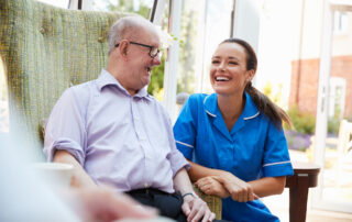 A memory care nurse laughs and smiles with a senior resident