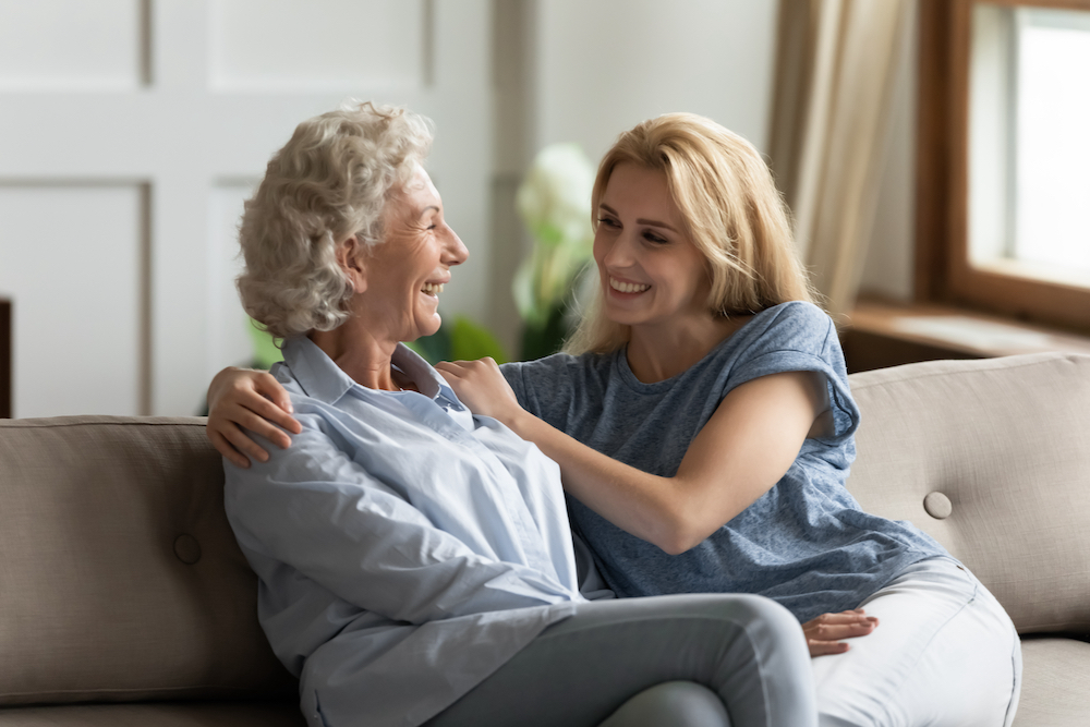 An adult woman and her senior mother talk on a sofa