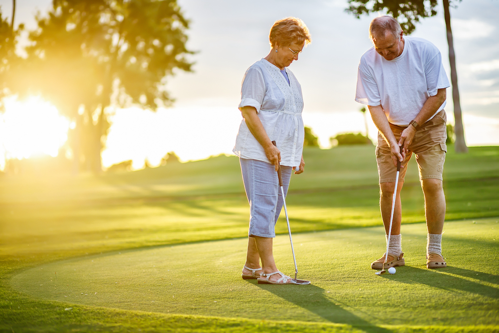 An active senior couple golf together