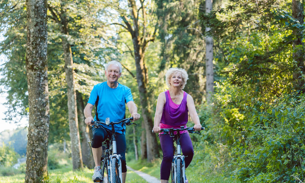 An active senior couple going on a bike ride in the woods