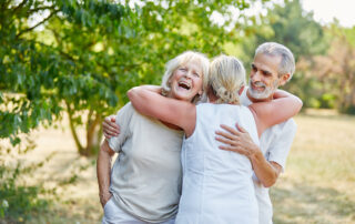 Three happy senior friends hug at assisted living