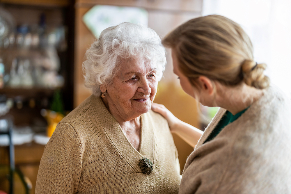 A senior woman talks with the staff at memory care services