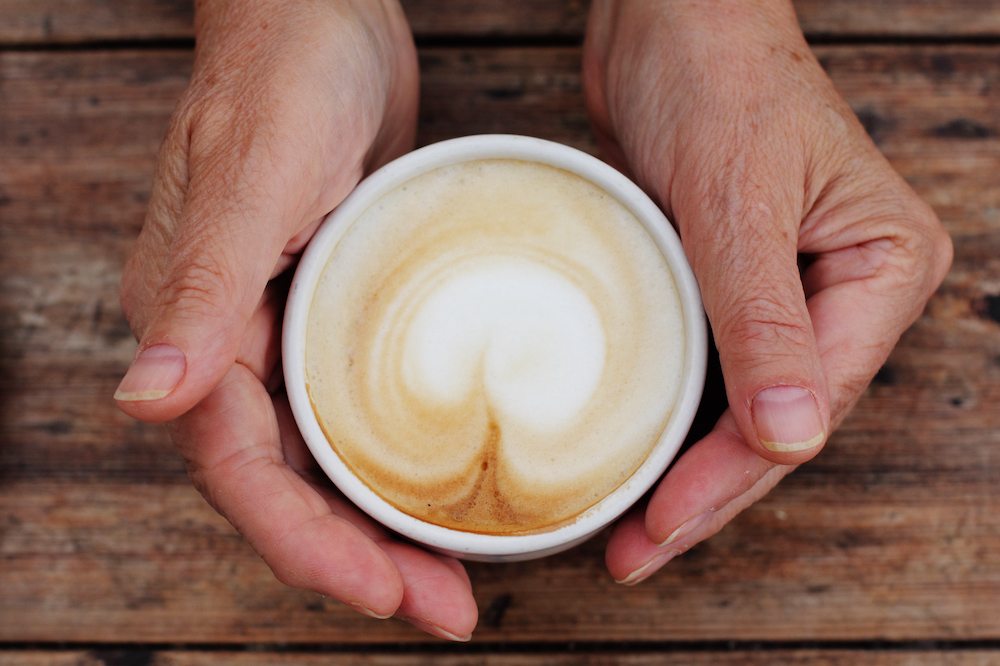 A senior woman holds onto a cup of coffee