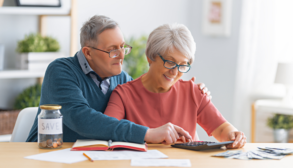 A happy senior couple calculates the cost of moving to senior living in Carlsbad, CA