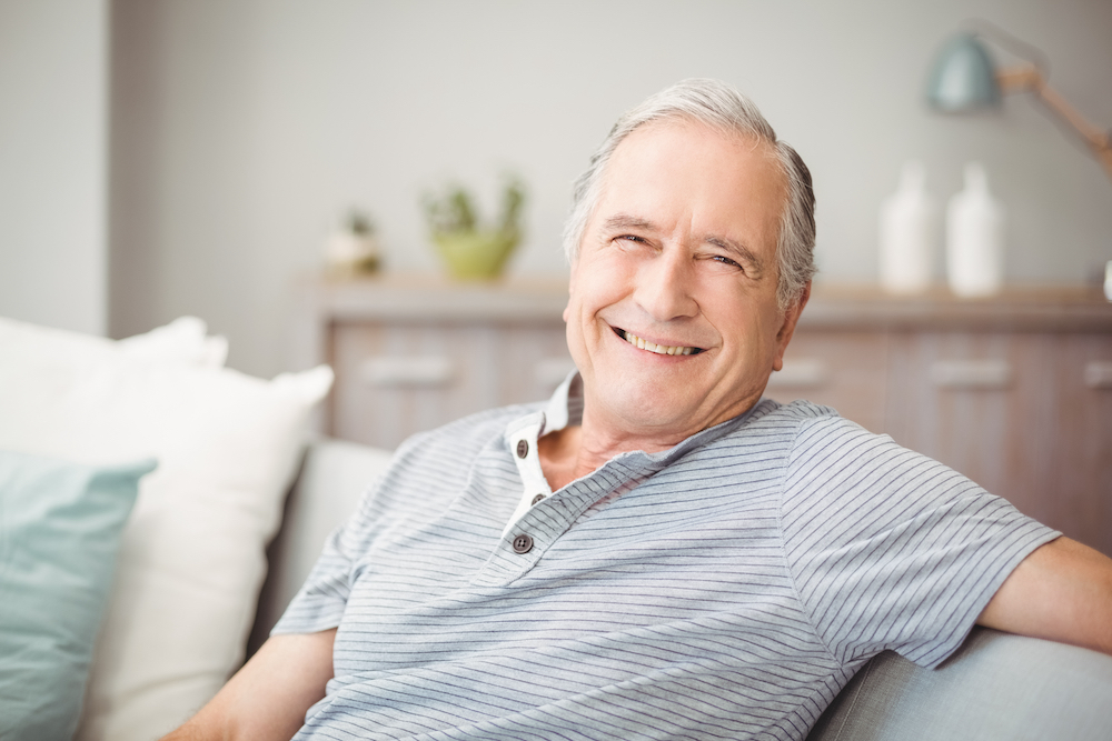 A happy senior man sitting on sofa and smiling