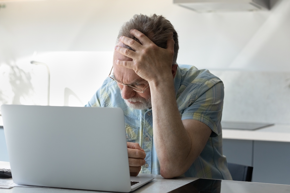 An upset senior man sitting in front of his laptop