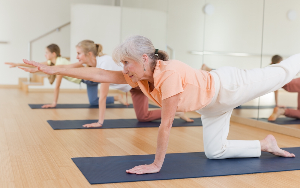 A resident of the senior living in Oceanside doing a yoga routine indoors