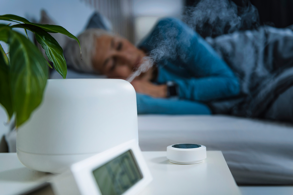 A senior woman sleeping at night while using a humidifier and a sound machine