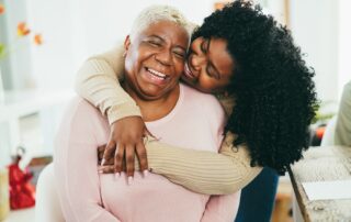 A young woman hugs her senior mother who uses memory care services
