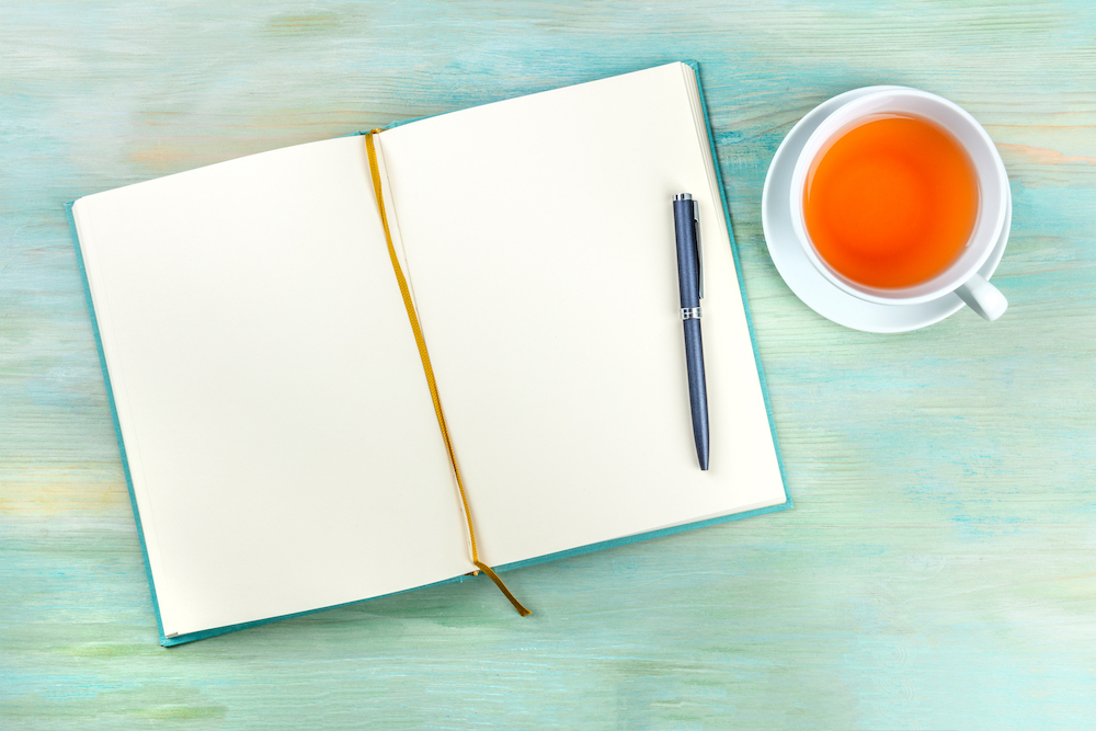 An open journal with a cup of tea