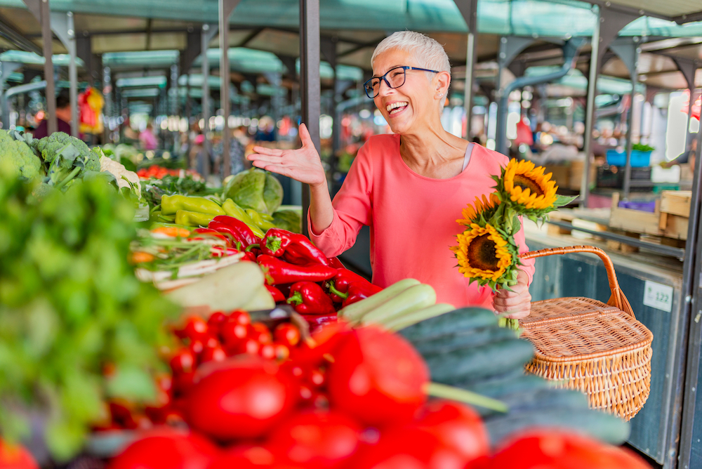 A happy senior woman visits the farmer's market