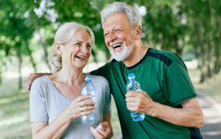 A senior couple on a hike and holding water bottles at the independent living in Carlsbad