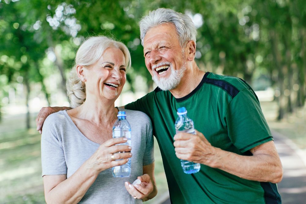 A senior couple on a hike and holding water bottles at the independent living in Carlsbad