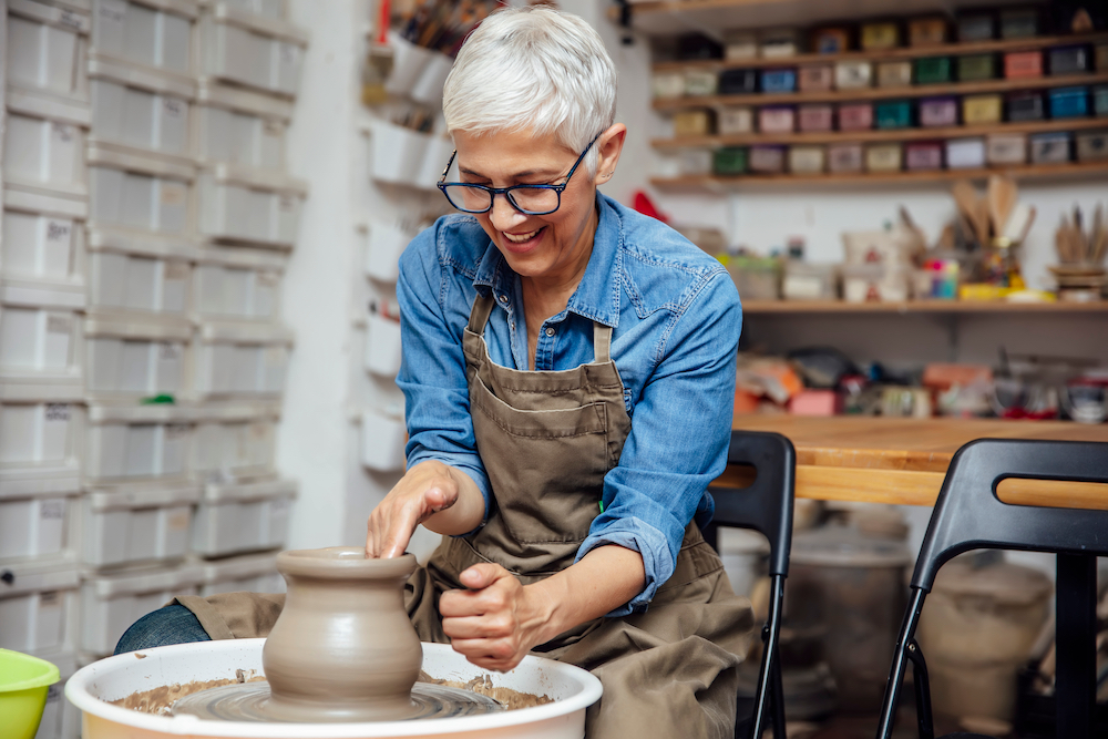 A happy senior woman smiles while taking a pottery class