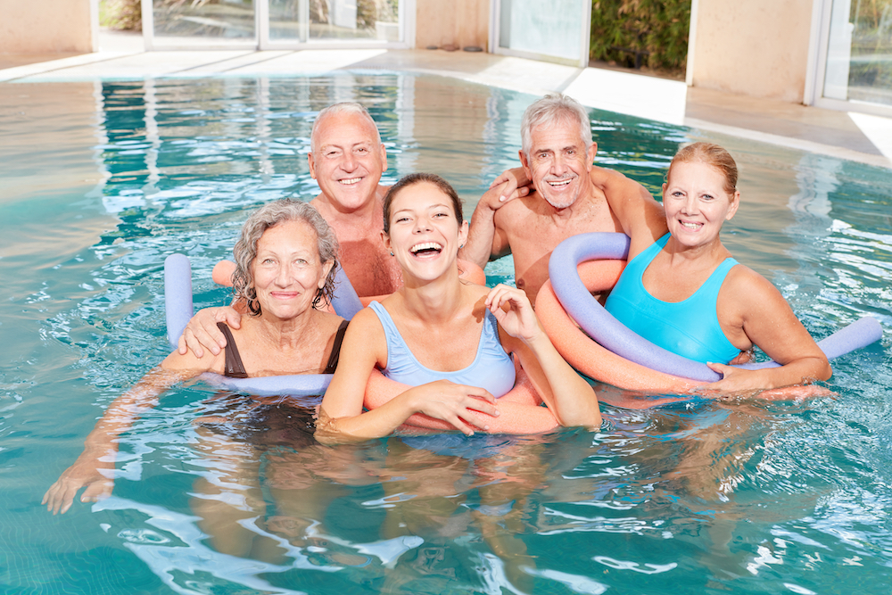 A group of senior friends take a water aerobics class lead by an instructor 