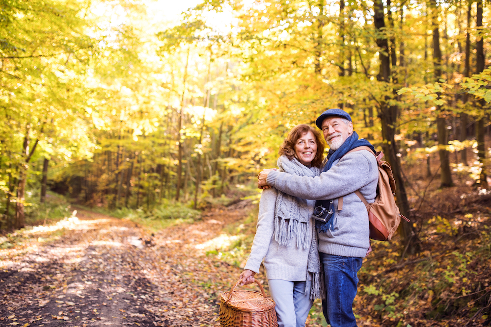 A senior couple on a fall walk outdoors at a park