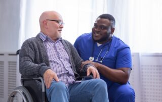 A senior man sits and talks with a caregiver