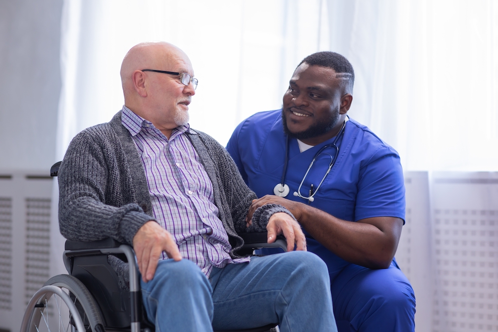 A senior man sits and talks with a caregiver