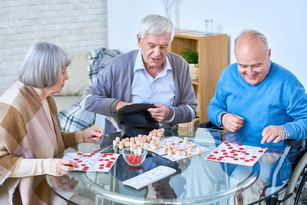 Three senior friends play a board game together at the best memory care in Carlsbad