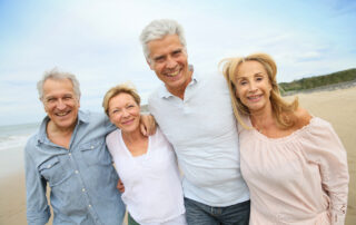 Two sets of senior couples go for a walk along a beach