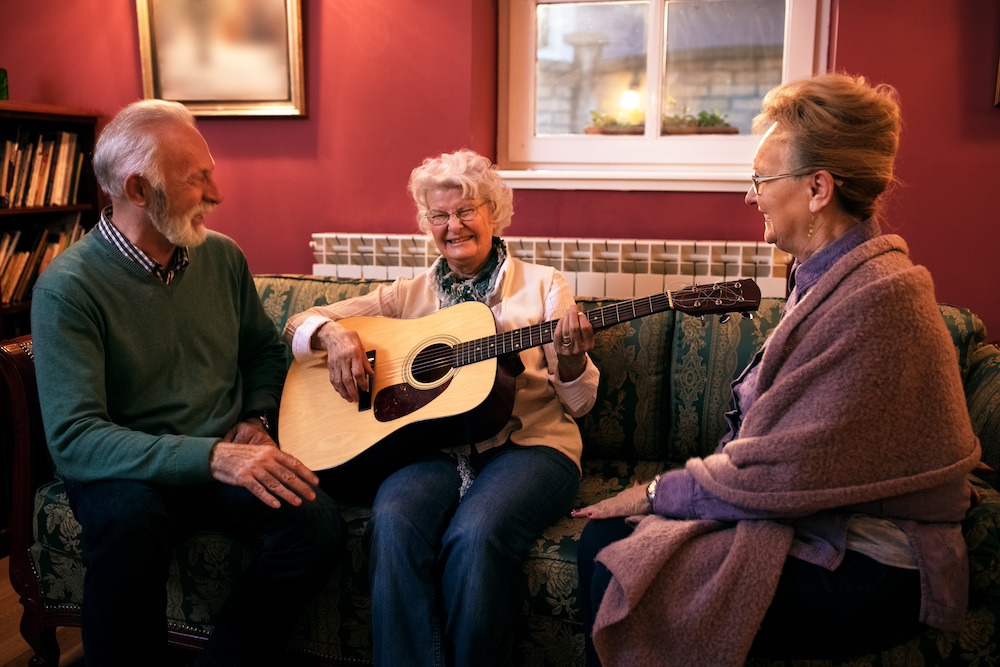 A senior woman plays guitar for her friends at the best assisted living in Oceanside