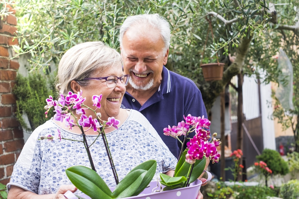 Happy senior couple outside with orchid plant enjoying the freedom of independent living carlsbad