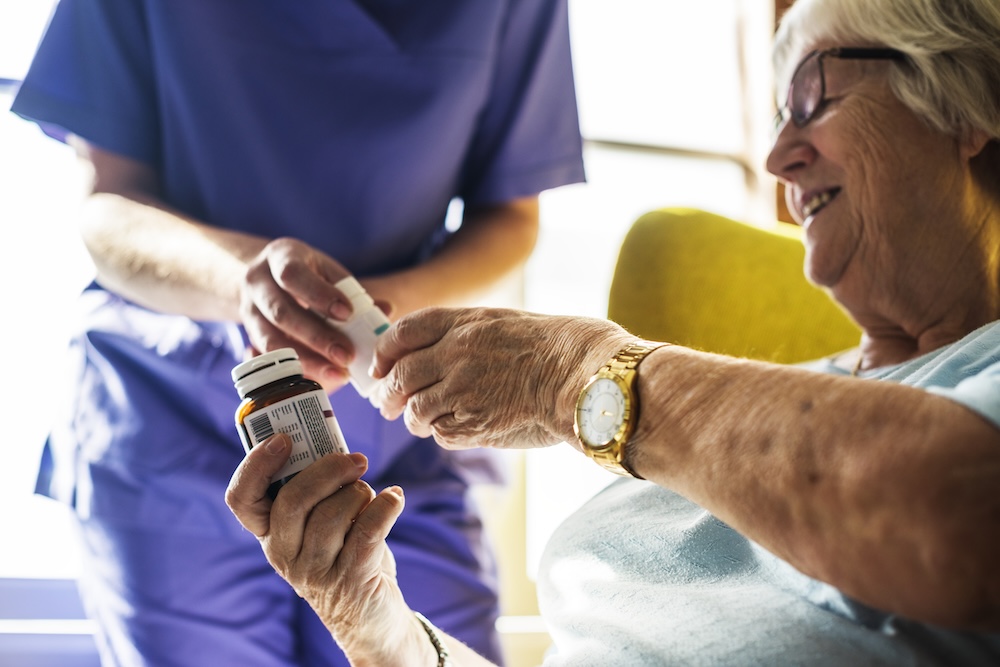 Senior woman taking her meds with the help of a nurse at senior living in carlsbad ca