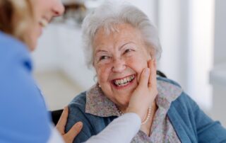 Caregiver helping a happy senior woman at their memory care carlsbad