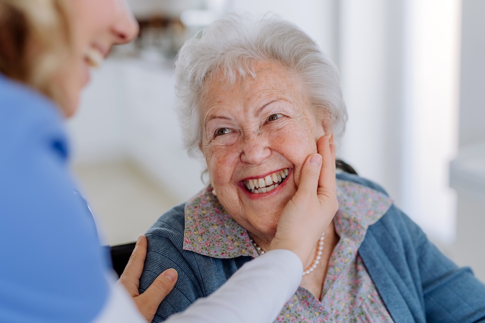 Caregiver helping a happy senior woman at their memory care carlsbad