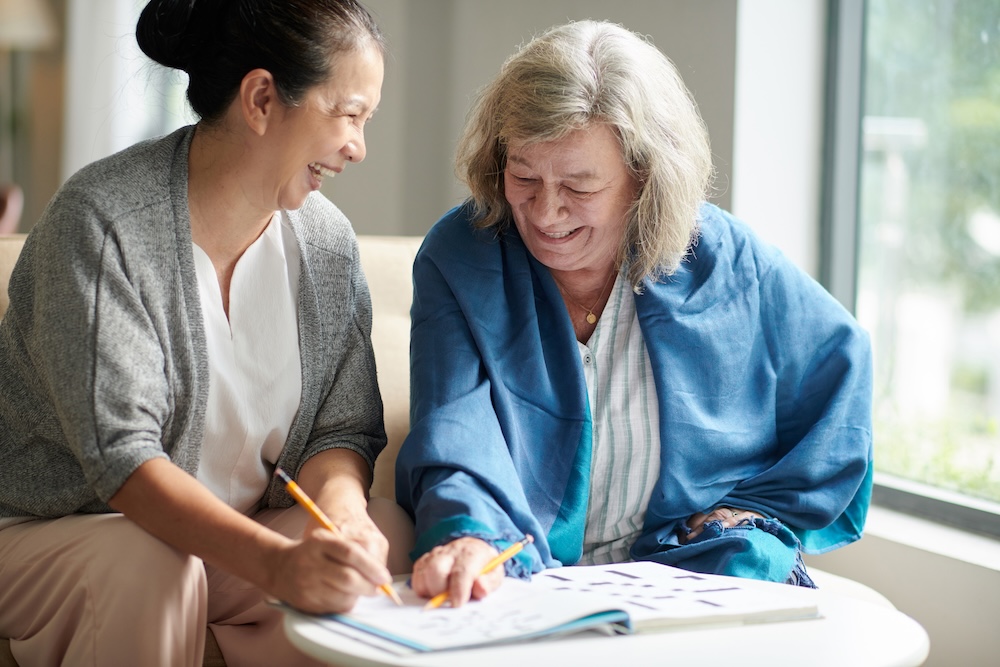Senior woman with caregiver working on puzzle together at her memory care carlsbad