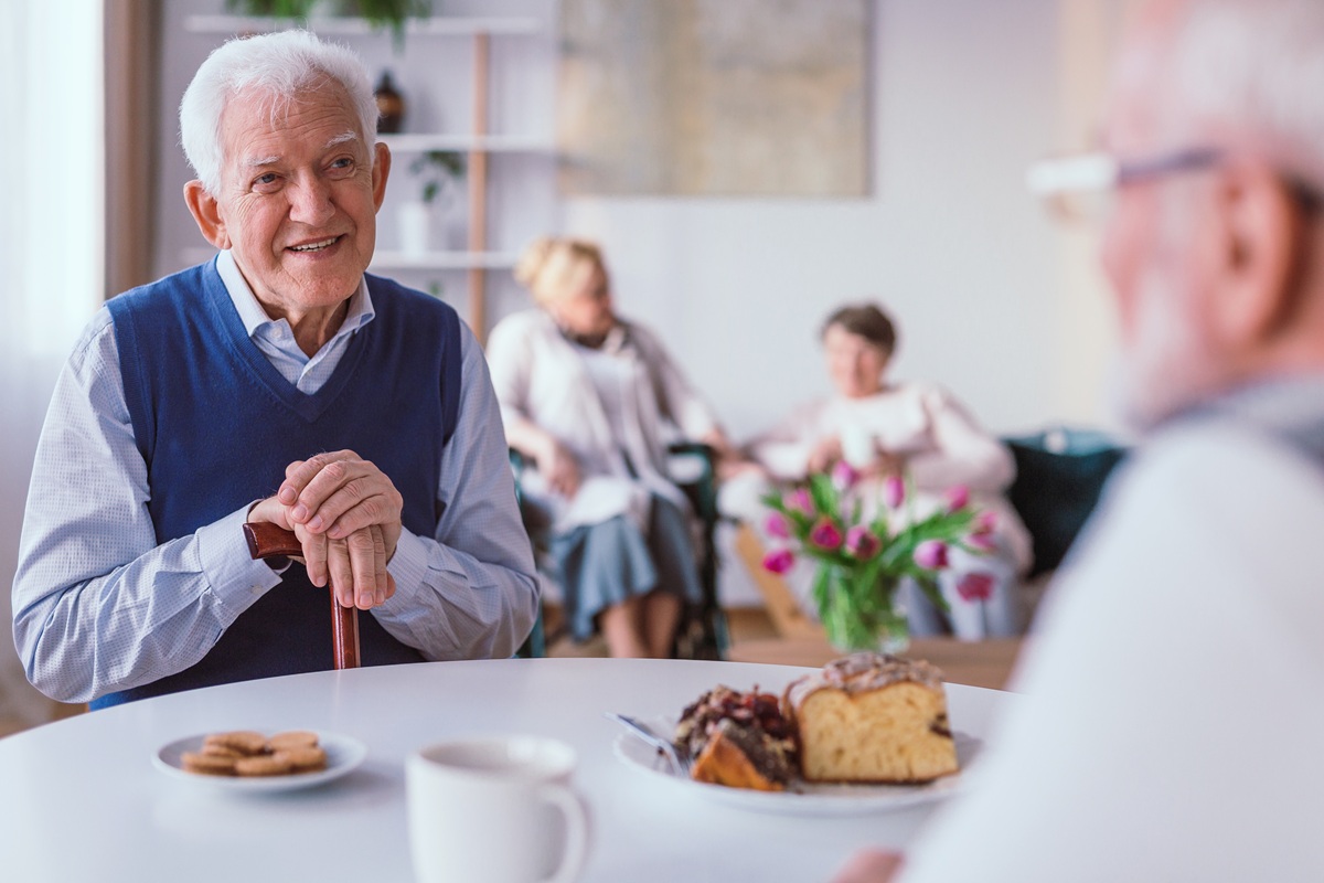 Senior living residents talking and laughing together over a meal after settling into community life